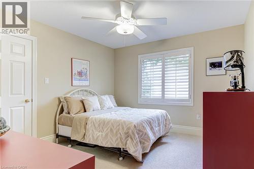 Bedroom featuring light-colored walls, carpeted flooring, a window with white louvered shutters, and a ceiling fan with an integrated light fixture - 4278 Clubview Drive, Burlington, ON - Indoor Photo Showing Bedroom