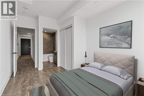 This property features light-colored walls, wood-style flooring, and a modern bathroom with a tiled shower - 4878 Powers Common Unit# 224, Burlington, ON - Indoor Photo Showing Bedroom