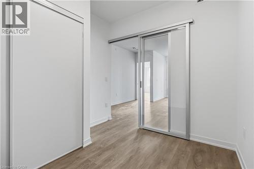 Interior space featuring light wood-style flooring, white walls, and a sliding glass door with a frosted panel - 4878 Powers Common Unit# 224, Burlington, ON - Indoor Photo Showing Other Room