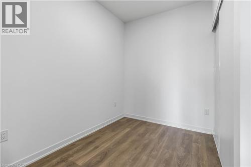 This room features light-colored walls, wood-style flooring, and a sliding door - 4878 Powers Common Unit# 224, Burlington, ON - Indoor Photo Showing Other Room