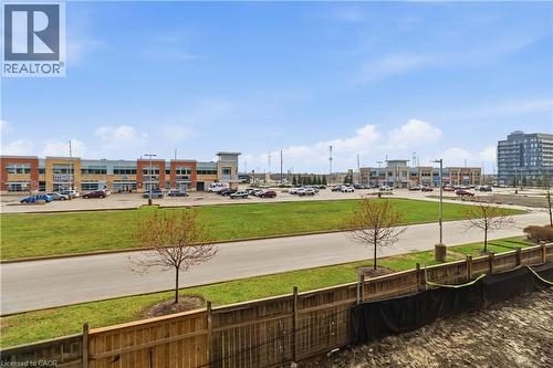 The property offers views of commercial buildings with varied facades, a parking area, and green spaces - 4878 Powers Common Unit# 224, Burlington, ON - Outdoor With View