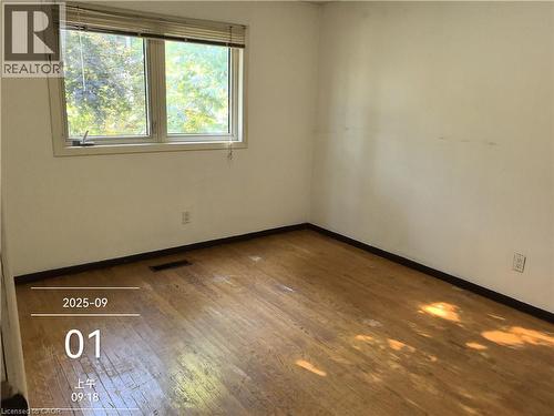 This room features hardwood flooring and a large window providing views of greenery - 134 Greenbrier Drive, Waterloo, ON 