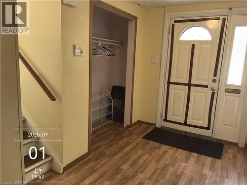 The entryway features wood-look flooring, a closet with shelving, and a stairway with a wooden handrail - 134 Greenbrier Drive, Waterloo, ON 