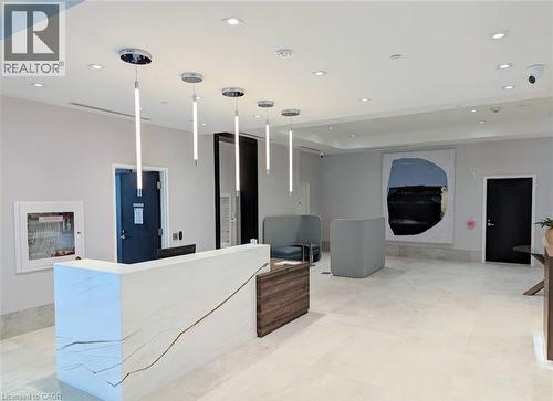 The property features a reception area with a white desk, recessed lighting, and modern pendant light fixtures - 385 Winston Road Unit# 1607, Grimsby, ON - Indoor Photo Showing Other Room