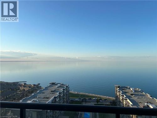 Expansive water views from a balcony with a glass railing, overlooking nearby buildings and a clear horizon - 385 Winston Road Unit# 1607, Grimsby, ON - Outdoor With Body Of Water With View