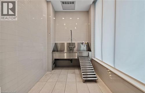Dedicated grooming area featuring tiled walls and floors, two stainless steel wash basins, and a ramp for ease of access - 385 Winston Road Unit# 1607, Grimsby, ON - Indoor Photo Showing Other Room