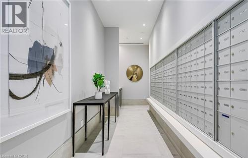 The property features a well-lit corridor with recessed lighting, a long console table, and a wall of mailboxes - 385 Winston Road Unit# 1607, Grimsby, ON - Indoor Photo Showing Other Room