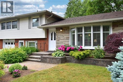 The property features a charming exterior with brick and stone accents, white siding, and a prominent bay window - 626 Vanderburgh Drive, Burlington, ON - Outdoor