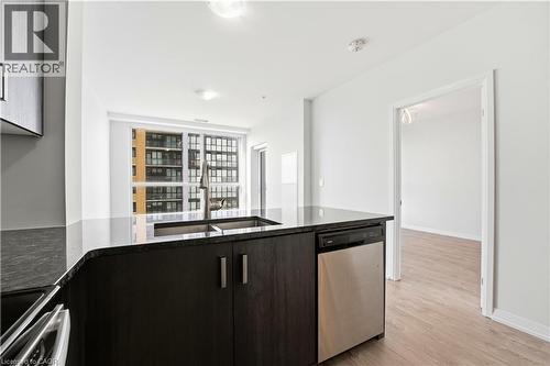 The kitchen features dark wood cabinetry, a stainless steel dishwasher, and a double sink - 104 Garment Street Unit# 1206, Kitchener, ON - Indoor Photo Showing Kitchen With Double Sink With Upgraded Kitchen