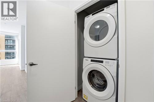 This property features a convenient stacked white washer and dryer unit, designed for efficient use of space - 104 Garment Street Unit# 1206, Kitchener, ON - Indoor Photo Showing Laundry Room