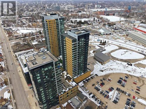 An aerial view showcasing the property's surrounding environment, including a street with cars, urban buildings, and a parking lot - 104 Garment Street Unit# 1206, Kitchener, ON - Outdoor With View
