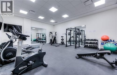 Fitness center featuring an exercise bike, an elliptical trainer, weight racks, and a weight bench, with wall-mounted mirrors and televisions - 104 Garment Street Unit# 1206, Kitchener, ON - Indoor Photo Showing Gym Room