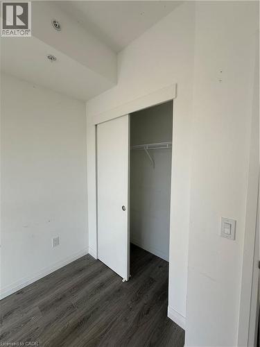 Room featuring dark wood-style flooring, white walls, and a closet with sliding doors - 108 Garment Street S Unit# 708, Kitchener, ON - Indoor Photo Showing Other Room