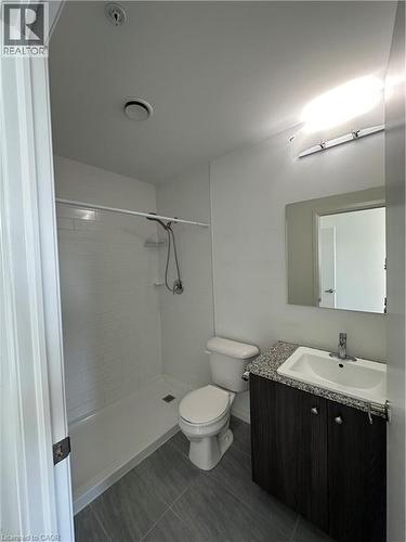 The bathroom features a walk-in shower with white subway tile, a vanity with a granite countertop and dark wood cabinetry, and tiled flooring - 108 Garment Street S Unit# 708, Kitchener, ON - Indoor Photo Showing Bathroom