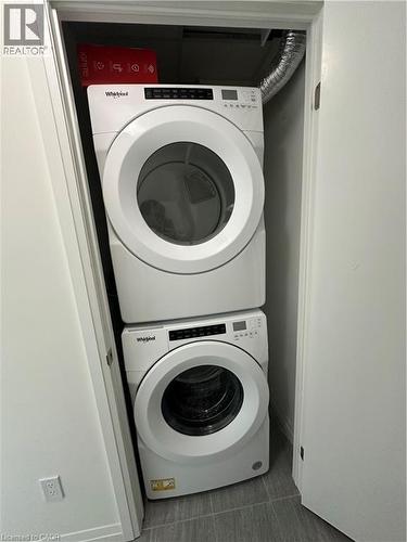 Laundry area featuring a stacked washer and dryer unit, set within a closet with a white door - 108 Garment Street S Unit# 708, Kitchener, ON - Indoor Photo Showing Laundry Room