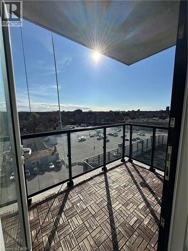 The property features a balcony with patterned wood tile flooring and a glass railing, offering expansive views of the surrounding area and a clear sky - 108 Garment Street S Unit# 708, Kitchener, ON -  With View