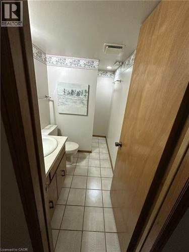 The bathroom features a vanity with an integrated sink, a toilet, and tiled flooring - 70 Bechtel Drive, Kitchener, ON - Indoor Photo Showing Bathroom