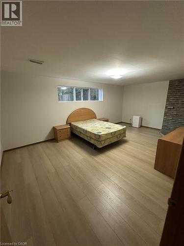 Expansive room featuring light wood-style flooring, a horizontal window, and a stone accent wall - 70 Bechtel Drive, Kitchener, ON - Indoor Photo Showing Bedroom