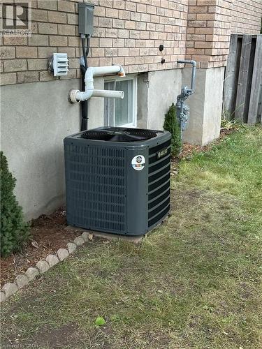 The property features an air conditioning unit, a brick exterior, a window, and a fenced area visible in the yard - 70 Bechtel Drive, Kitchener, ON - Outdoor