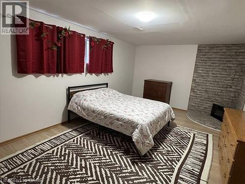 Room featuring light-toned flooring, a window with dark red curtains, and a stone-clad corner fireplace with a hearth - 70 Bechtel Drive, Kitchener, ON - Indoor Photo Showing Bedroom