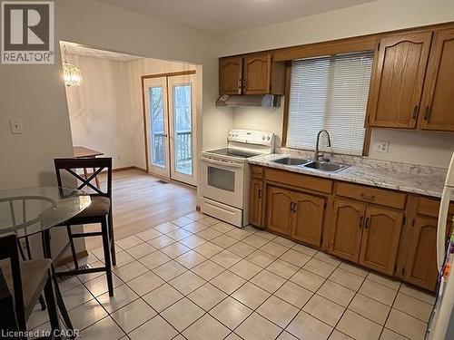 Kitchen featuring tile flooring, wood-finish cabinetry, a double basin sink, and a white electric range - 70 Bechtel Drive, Kitchener, ON - Indoor Photo Showing Kitchen With Double Sink