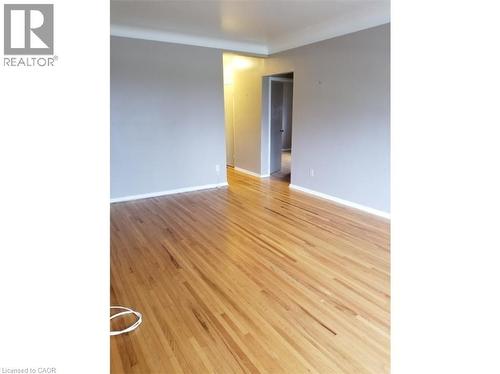 This interior space features hardwood floors and walls finished in a neutral tone - 981 Mohawk Road E, Hamilton, ON - Indoor Photo Showing Other Room