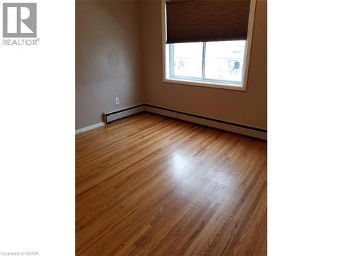 Room featuring hardwood floors, a window with blinds, and baseboard heating - 981 Mohawk Road E, Hamilton, ON - Indoor Photo Showing Other Room