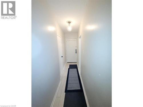 The property features a hallway with light-colored flooring, white walls, and a ceiling light fixture providing illumination - 981 Mohawk Road E, Hamilton, ON - Indoor Photo Showing Other Room