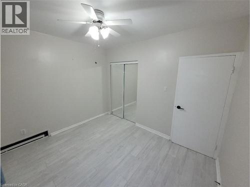 This room features light-colored flooring, a ceiling fan with integrated lighting, and a closet with mirrored sliding doors - 981 Mohawk Road E, Hamilton, ON - Indoor Photo Showing Other Room