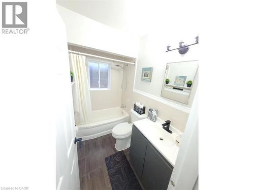 Bathroom featuring a vanity with a white countertop and a black faucet, a toilet, and a bathtub with a window - 981 Mohawk Road E, Hamilton, ON - Indoor Photo Showing Bathroom