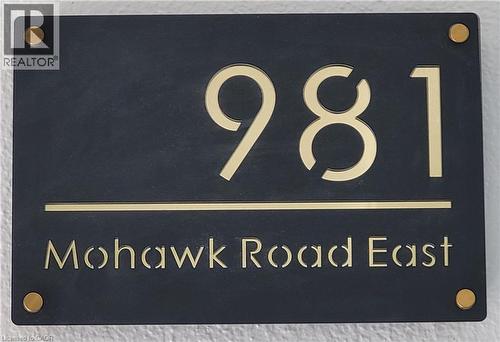 The property features a sleek black address plaque with gold-toned numbers and lettering - 981 Mohawk Road E, Hamilton, ON - 
