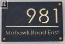 The property features a sleek black address plaque with gold-toned numbers and lettering - 981 Mohawk Road E, Hamilton, ON  -  