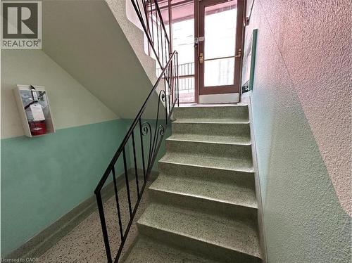 Stairwell featuring terrazzo steps, black wrought iron railings, and a two-toned wall - 981 Mohawk Road E, Hamilton, ON - Indoor Photo Showing Other Room
