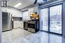 The kitchen features stainless steel appliances, white cabinetry, a patterned backsplash, and large sliding glass doors providing access to the outdoors - 687 Britannia Avenue, Hamilton, ON  - Indoor Photo Showing Kitchen With Stainless Steel Kitchen 