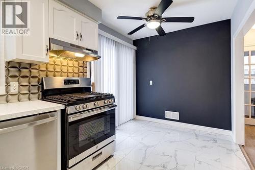 The kitchen features white cabinetry, a stainless steel range and dishwasher, and a patterned backsplash - 687 Britannia Avenue, Hamilton, ON - Indoor Photo Showing Kitchen
