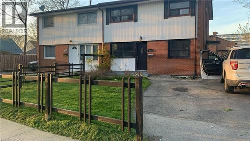 The property features a brick and siding exterior, a front lawn with a decorative fence, and a paved driveway - 687 Britannia Avenue, Hamilton, ON - Outdoor