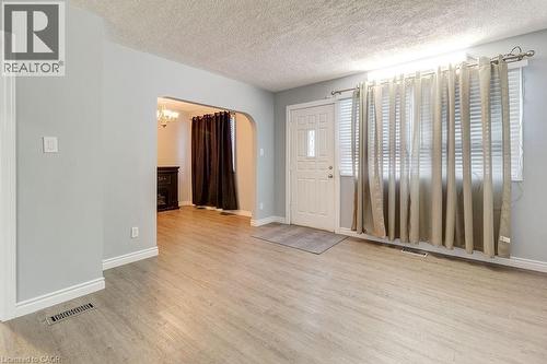 This inviting living area features light-toned flooring, light gray walls with white trim, and a prominent window with blinds - 687 Britannia Avenue, Hamilton, ON - Indoor Photo Showing Other Room