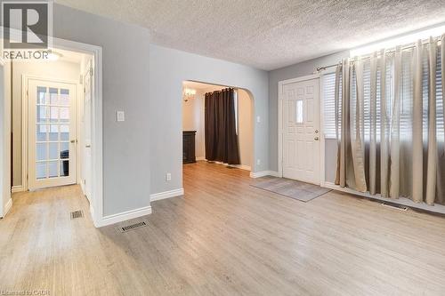 The property features light-toned flooring, a front entry door with a window, and a large window dressed with blinds and drapes - 687 Britannia Avenue, Hamilton, ON - Indoor Photo Showing Other Room