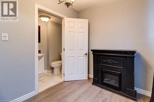 The interior features a black ornamental fireplace, wood tone flooring, and light grey walls - 687 Britannia Avenue, Hamilton, ON - Indoor With Fireplace