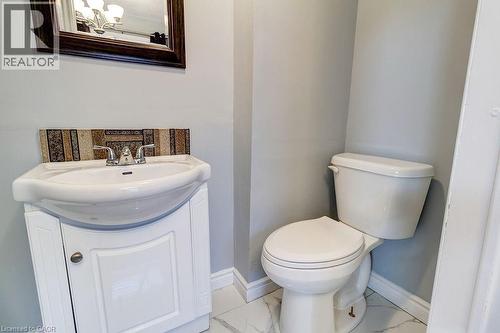 Bathroom featuring a white pedestal sink with a storage cabinet, a decorative tiled backsplash, a white toilet, and light-colored walls - 687 Britannia Avenue, Hamilton, ON - Indoor Photo Showing Bathroom
