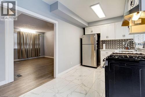Kitchen featuring white cabinetry, a stainless steel refrigerator, and a gas range - 687 Britannia Avenue, Hamilton, ON - Indoor Photo Showing Kitchen
