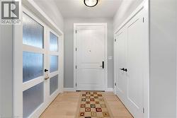 Entryway featuring light hardwood floors, white doors, a patterned runner, and a ceiling-mounted light fixture - 