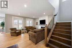The living area features light hardwood flooring, recessed lighting, and windows with white plantation shutters - 