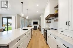 The kitchen features white cabinetry with black hardware, a long central island with a sink, and stainless steel appliances - 
