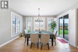 Dining area featuring light hardwood floors, white baseboards, and windows with white plantation shutters - 