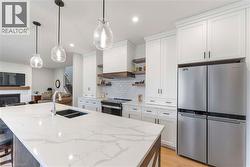 The kitchen features a spacious island with a white countertop and an undermount sink, complemented by white cabinetry and stainless steel appliances - 