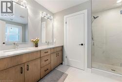 Bathroom with a double vanity featuring light wood cabinetry, white countertops, and contemporary light fixtures - 