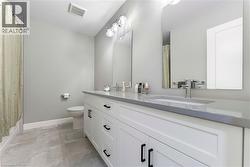 This bathroom features a double vanity with white cabinetry, black hardware, and a light-colored countertop, complemented by dual mirrors and contemporary lighting - 