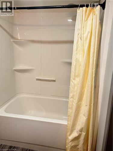 Bathroom featuring a tub and shower combination with integrated shelving - 275 Larch Street Unit# 108, Waterloo, ON - Indoor Photo Showing Bathroom