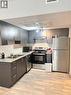 The kitchen features dark wood cabinetry, granite-style countertops, and light-toned flooring - 275 Larch Street Unit# 108, Waterloo, ON  - Indoor Photo Showing Kitchen With Double Sink 